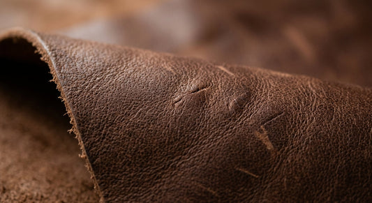 Macro of full-grain leather showing natural pore structure and irregular grain, with the fibrous underside visible.