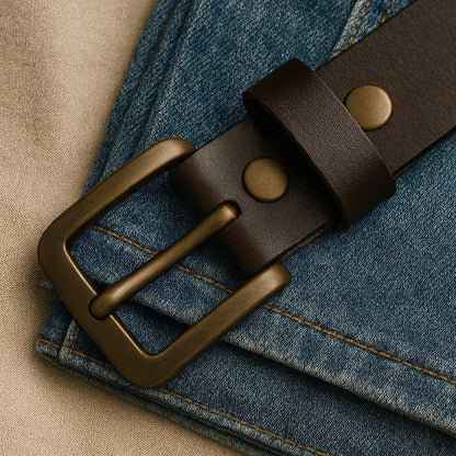 Brown leather belt with brass buckle on a denim background