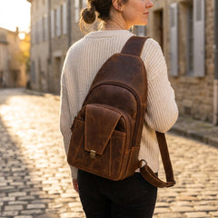 A woman wearing the Bellvari Metro Sling on her back, walking a cobbled street. — view 8