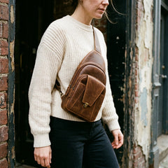 A woman wearing the Bellvari Metro Sling across her chest in brown crazy-horse leather. — view 6