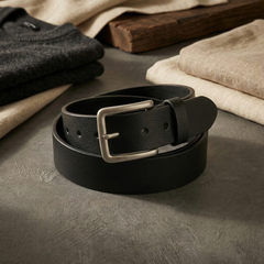 Bellvari Tradesman black full-grain leather belt coiled beside folded knitwear and linen, brushed steel buckle. — view 7