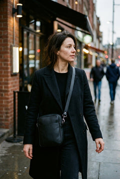 A woman wearing the black Bellvari YYZ Travel Satchel crossbody on a city street. — view 14