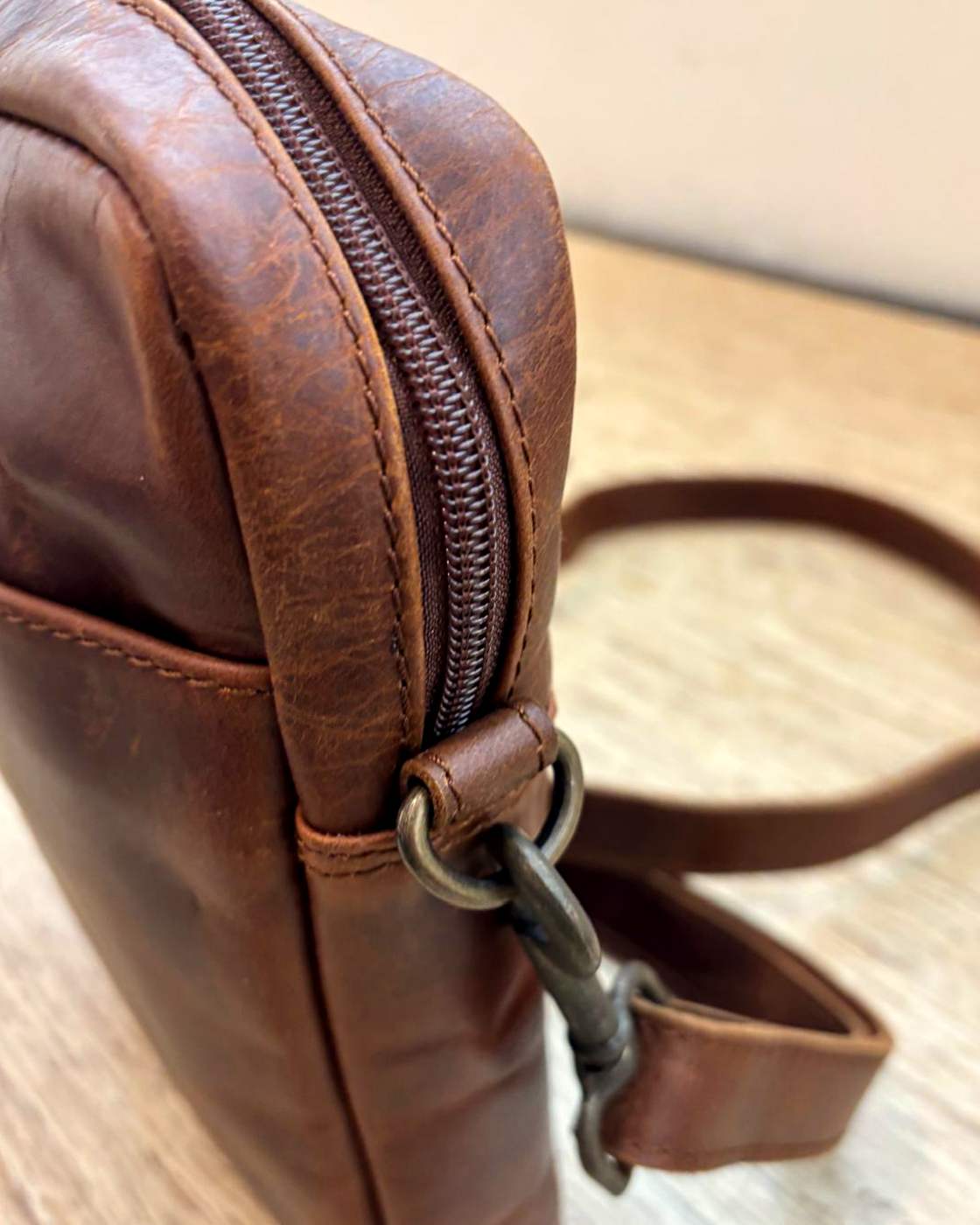 Real photo of the YYZ Satchel seen from the side, showing the depth of the gusset, the seam along the top edge, the top zip and the strap clipped to the D-ring.
